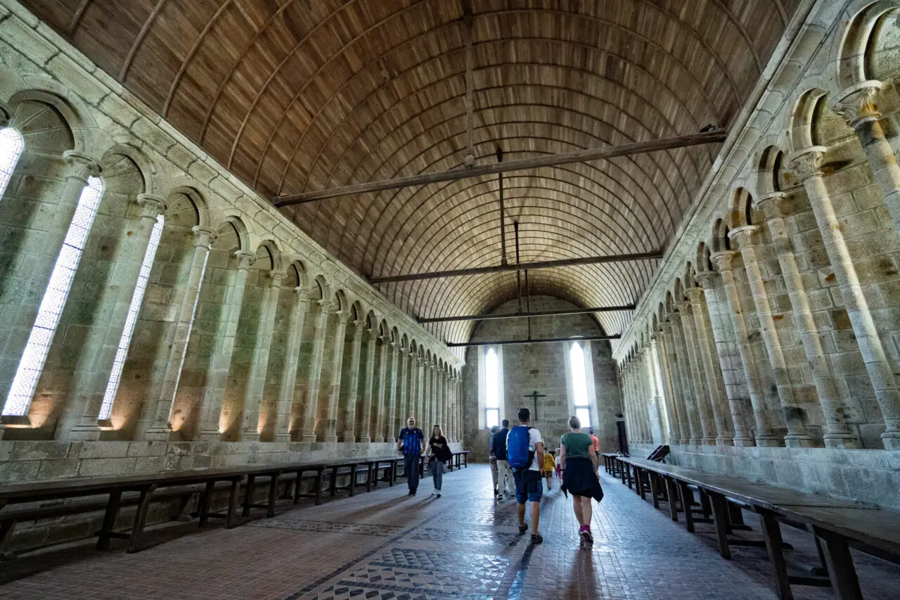 Réfectoire de l'abbaye du Mont Saint-Michel avec plafond en berceau en bois et murs de pierre avec fenêtres en arc