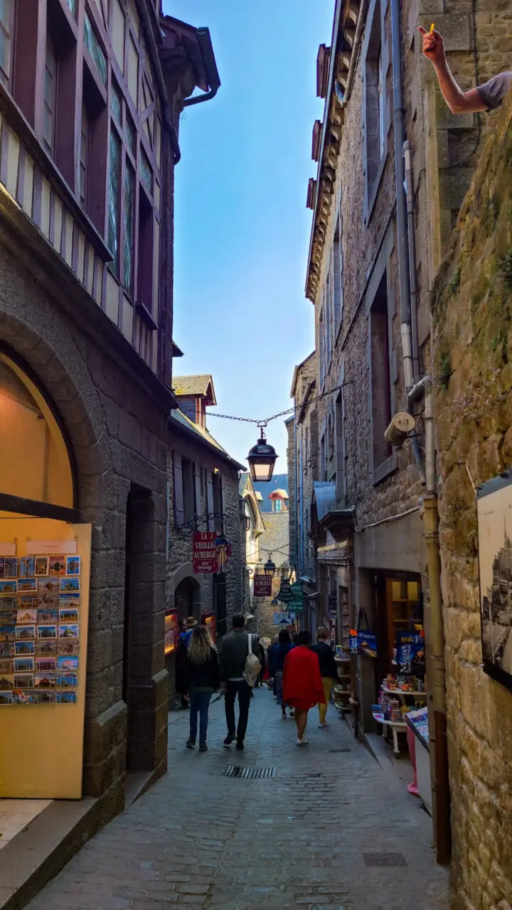 Ruelle pavée étroite à l'intérieur du Mont Saint-Michel avec bâtiments de pierre médiévaux et boutiques souvenirs
