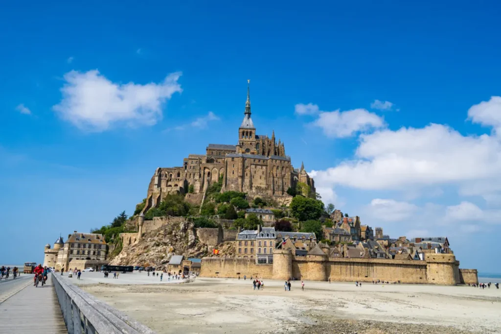 Vue rapprochée de l'abbaye du Mont Saint-Michel depuis la passerelle montrant l'architecture gothique et les murs médiévaux